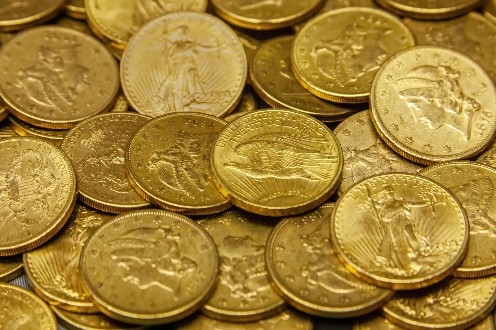 Macro photograph of luxury gold coins and bullion bars under warm lighting
