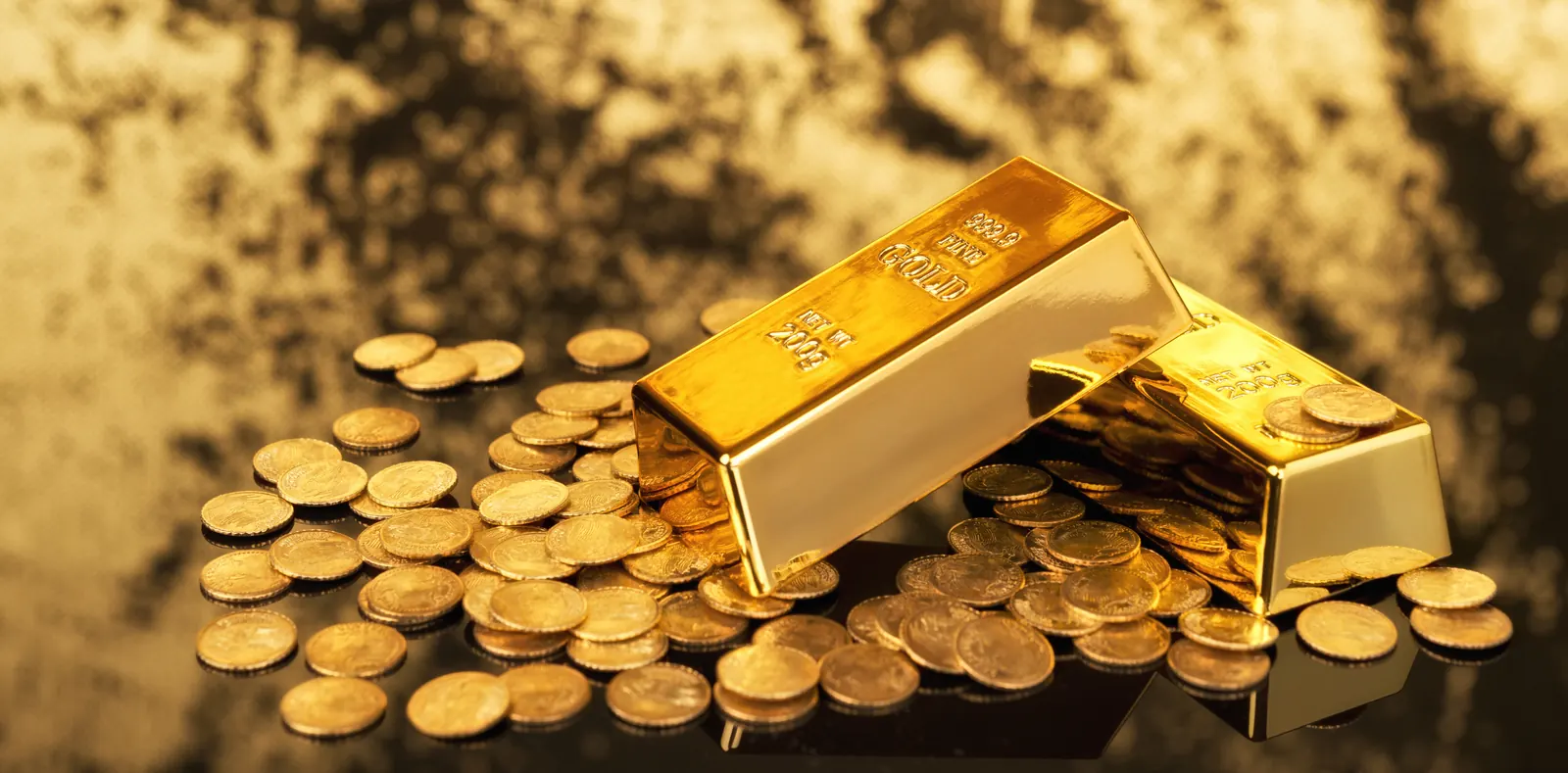 Gold ingots and assorted gold coins on a dark surface
