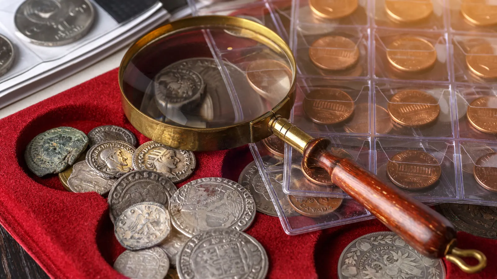 Vintage silver coins arranged in a collector's album with a magnifying glass